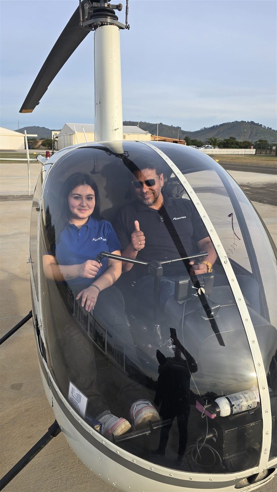 Dos personas con indumentaria de Aerolíder dentro de un helicóptero